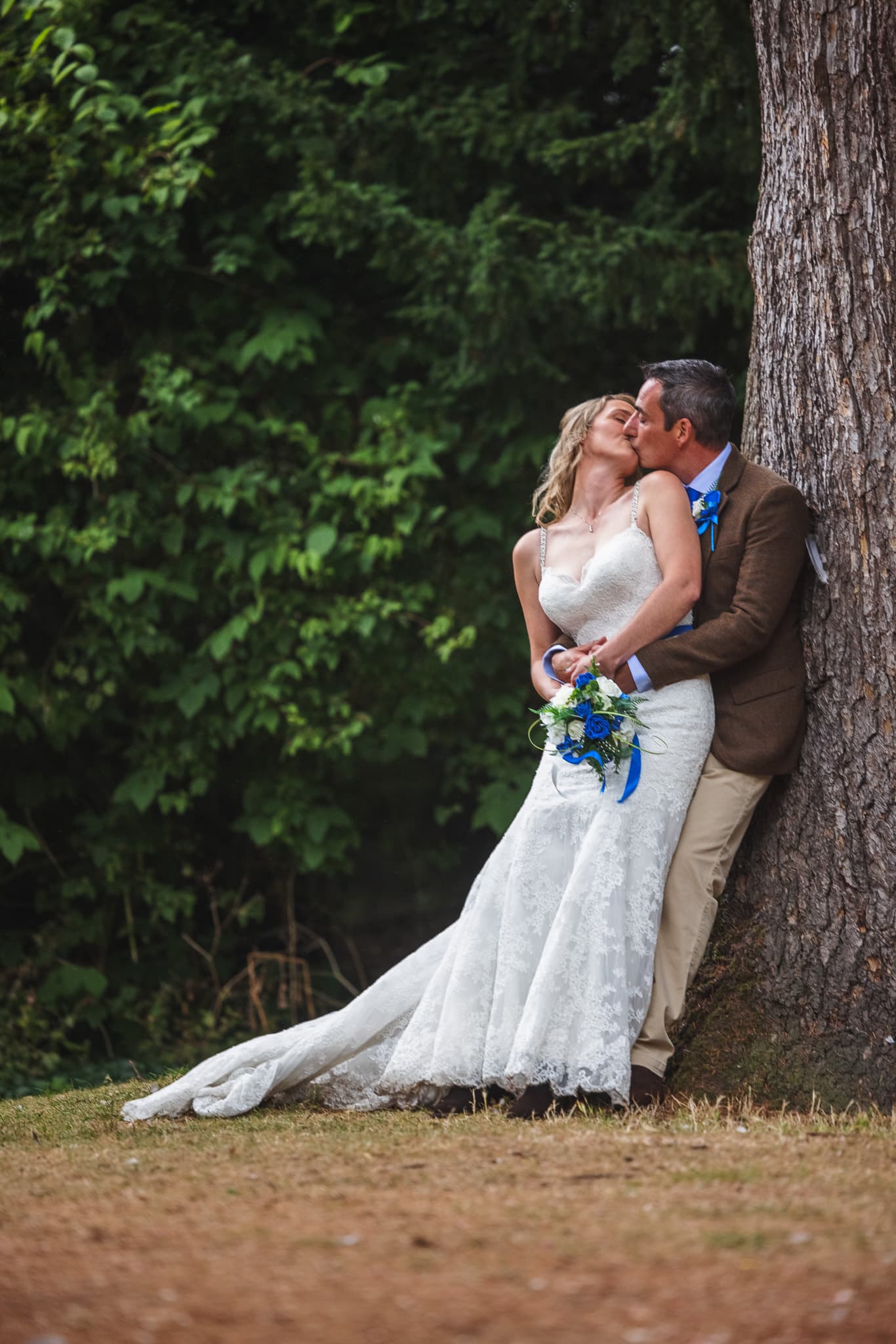 country couple lean aginst tree outdoor wedding